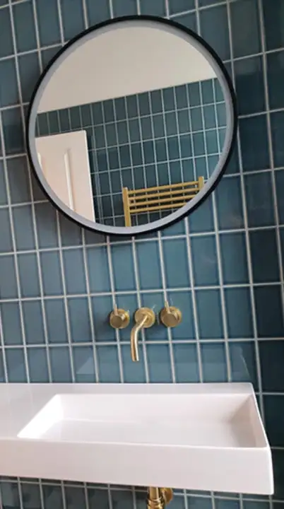 Round mirror and wall-mounted basin with brass taps