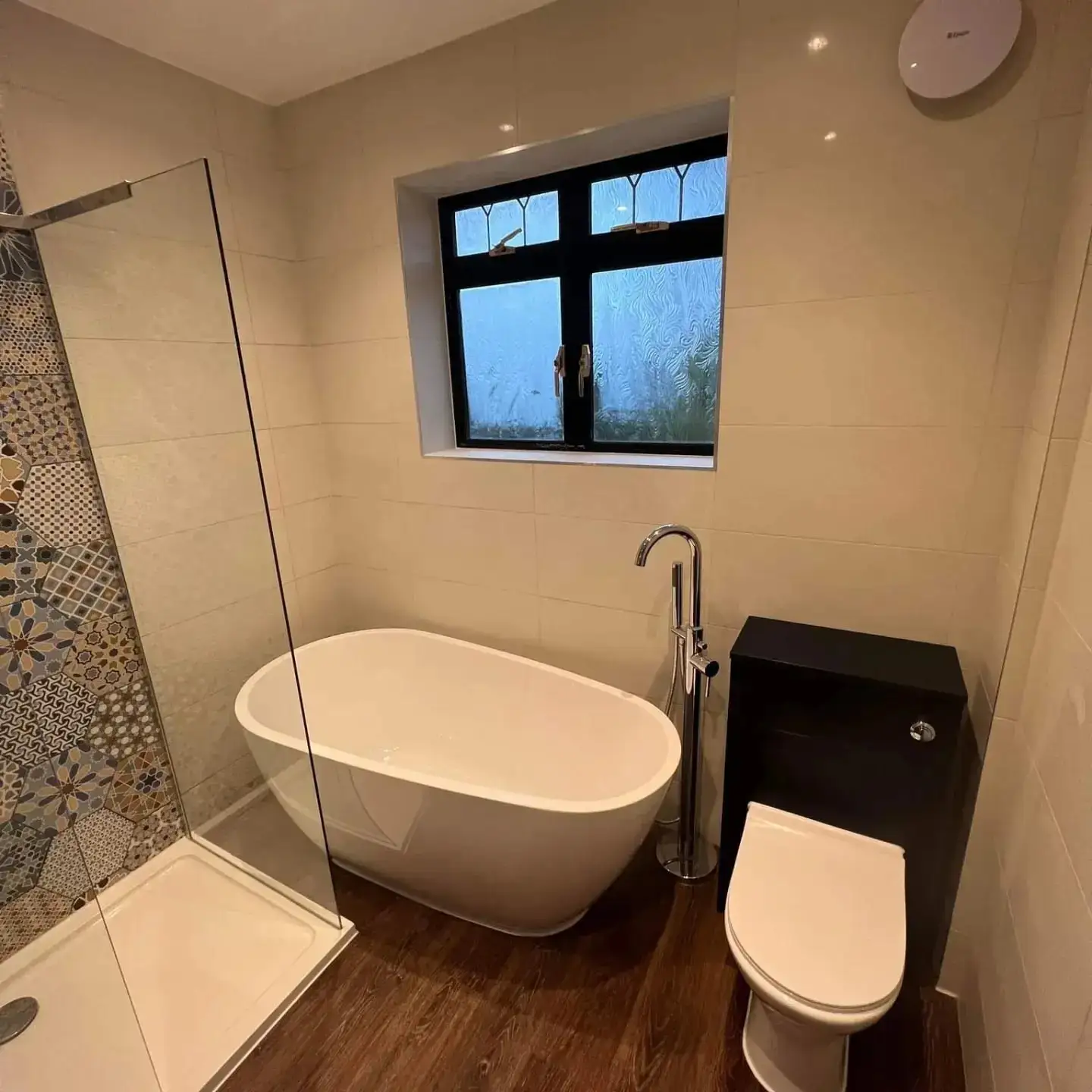 Bathroom with a freestanding bath, a walk-in shower with patterned hexagon tiles and a wood-effect floor