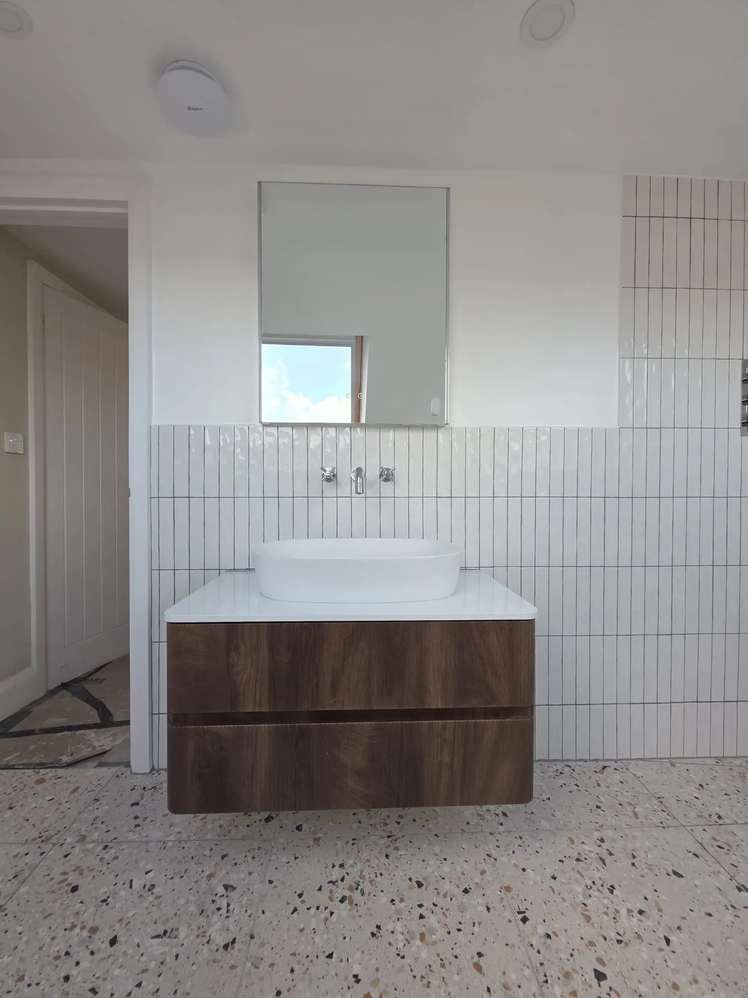 Wall-hung vanity with a marble top and vertical white tiles