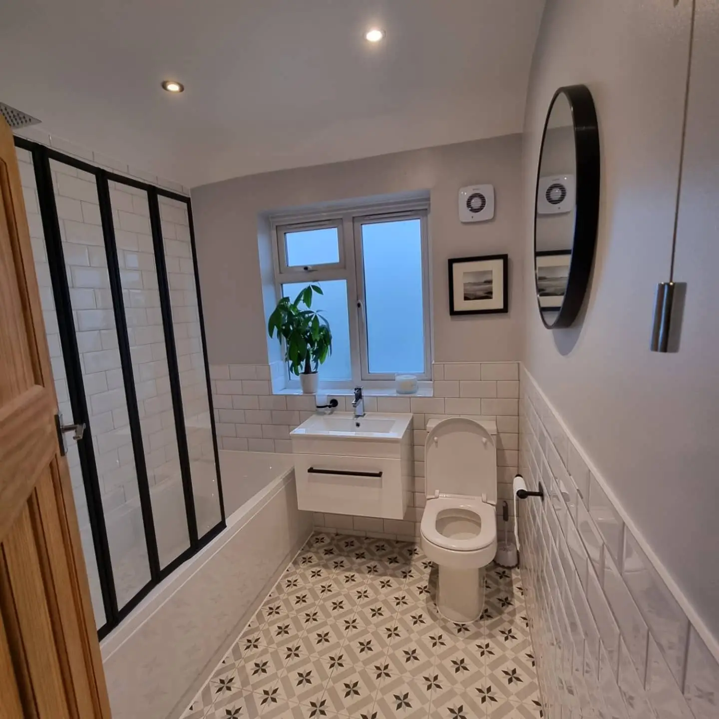 Metro tiles, a black framed shower screen and a patterned floor