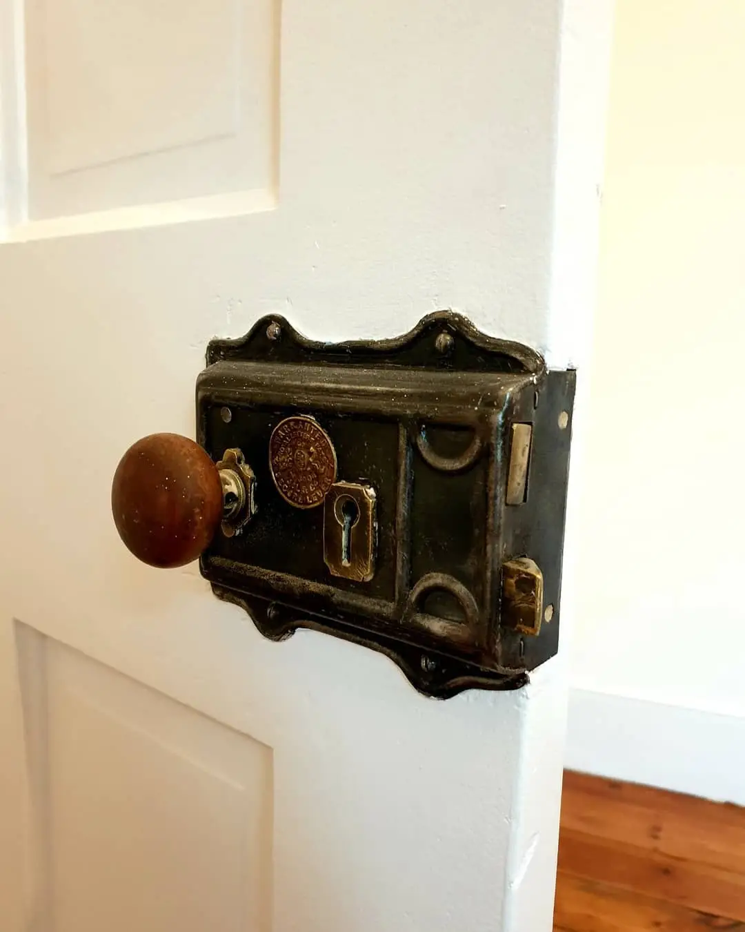 Period rim lock with a wooden knob refitted on a painted panel door