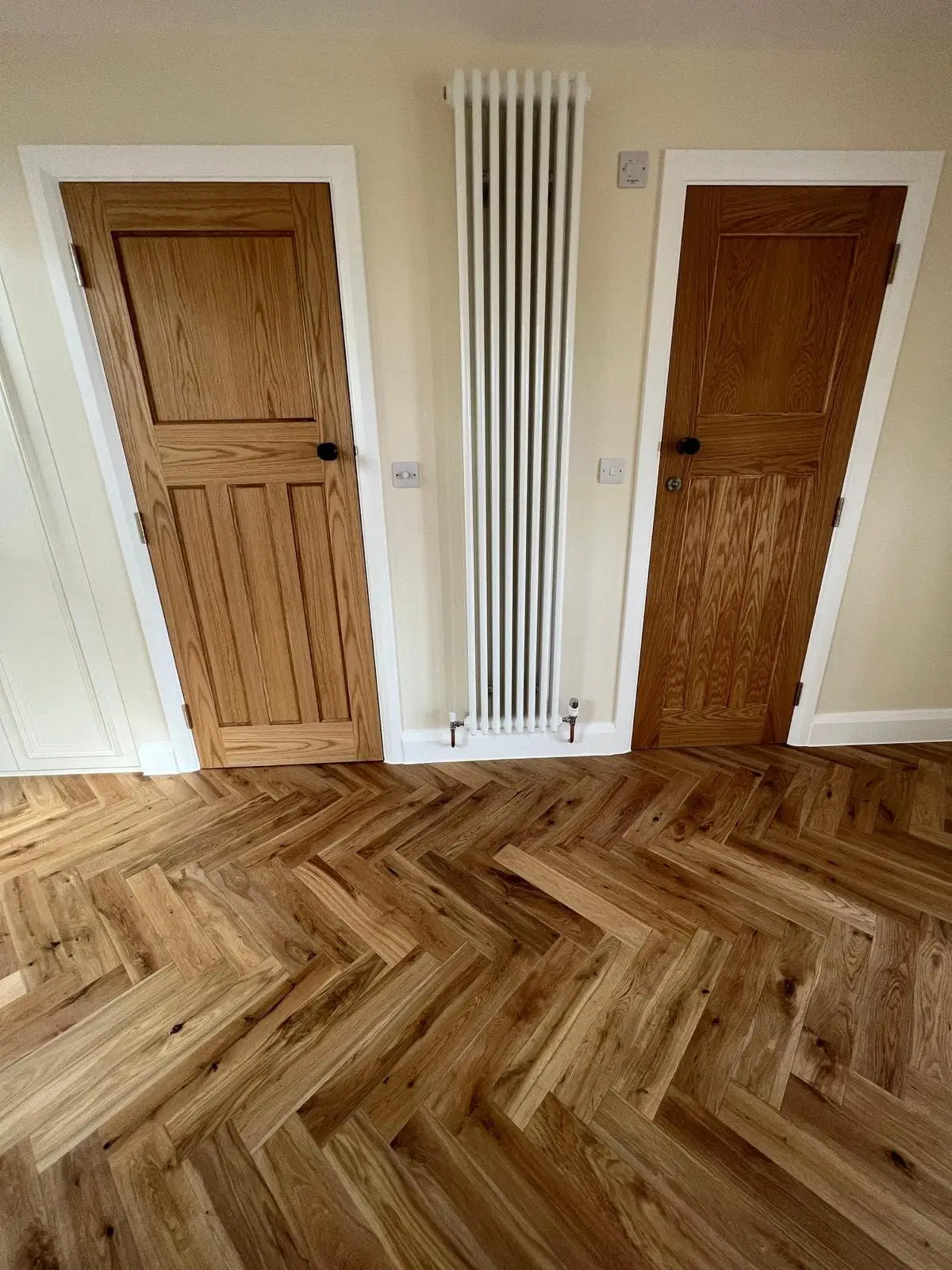 Oak panel doors, a tall column radiator and a herringbone floor on the new loft landing