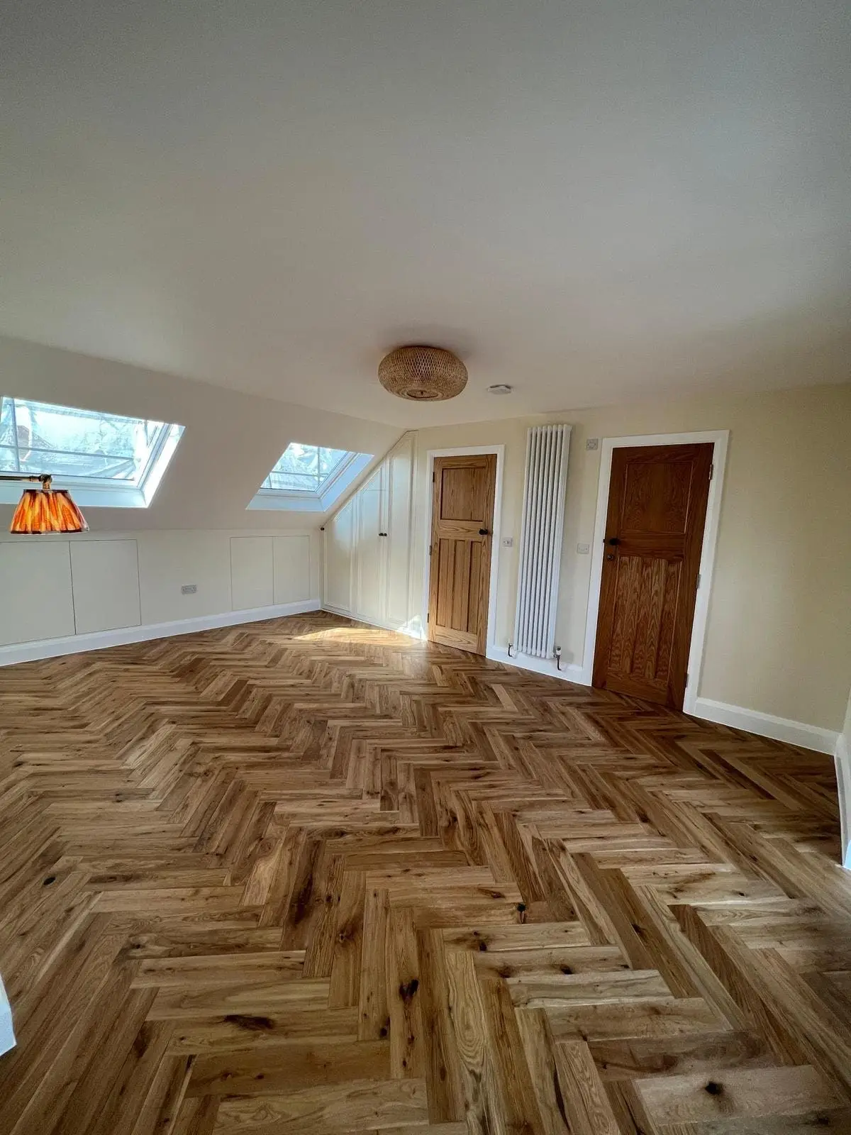 Loft bedroom with a herringbone oak floor under the roof windows