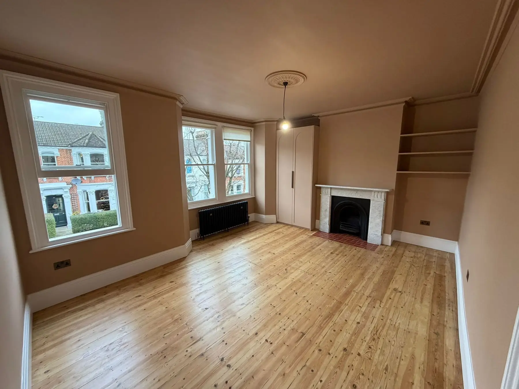 Refurbished main bedroom with a restored pine floor and alcove shelves